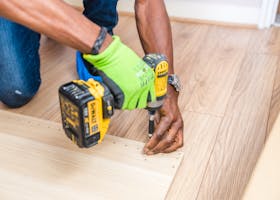 pexels-photo-1249610-1249610 Close-up of handyman drilling wood indoors with green gloves and cordless drill.